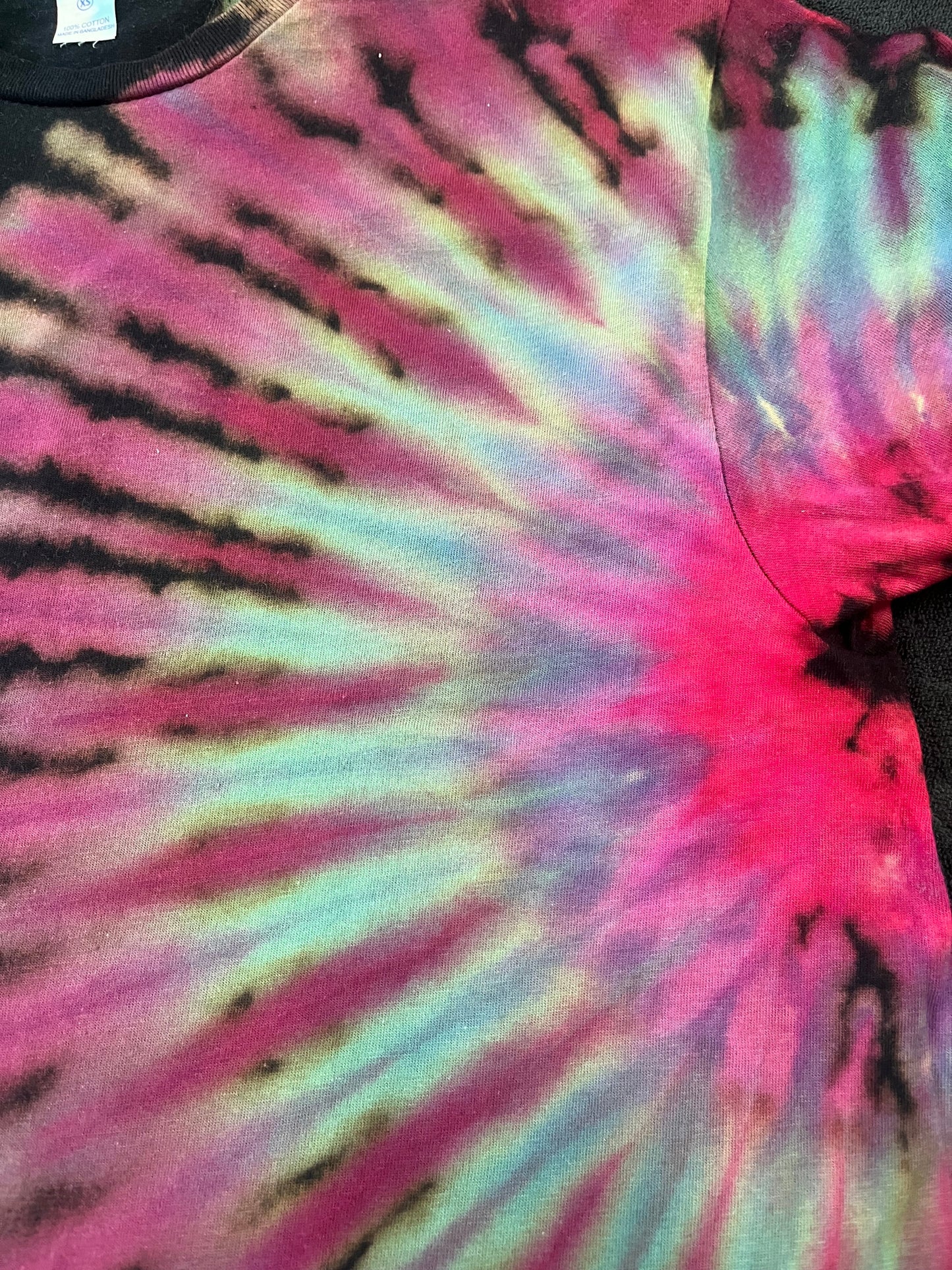 Close-up of a tie-dye pattern with pink, purple, and black colors.