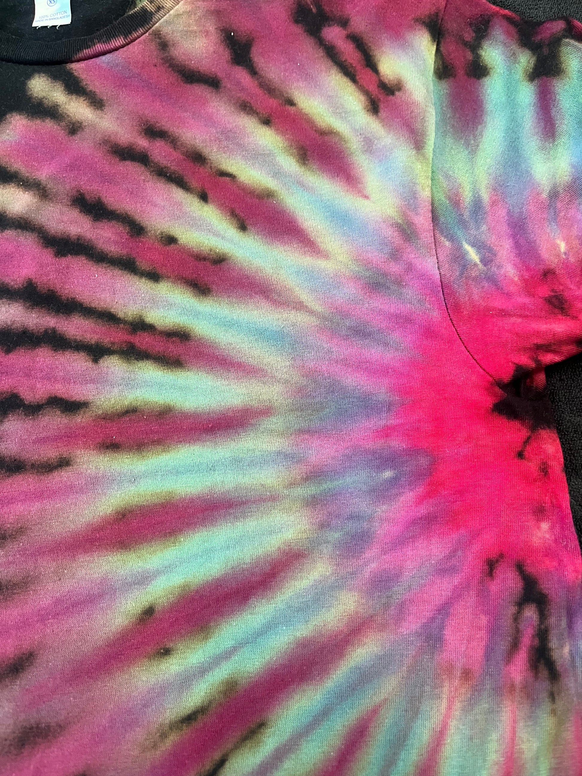 Close-up of a tie-dye pattern with pink, purple, and black colors.
